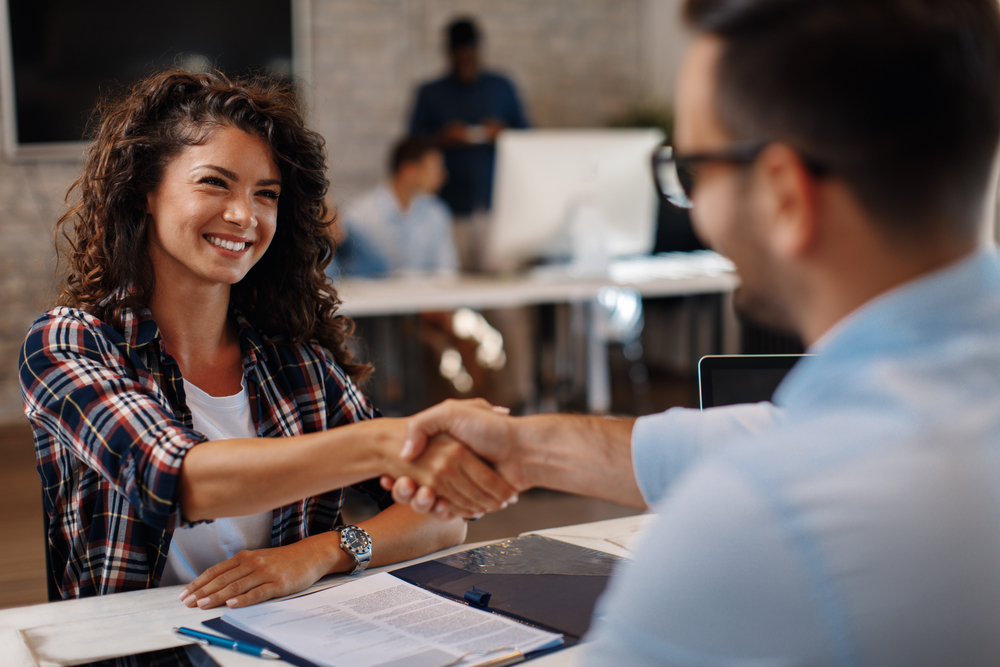 Young,Woman,Signing,Contracts,And,Handshake,With,A,Manager