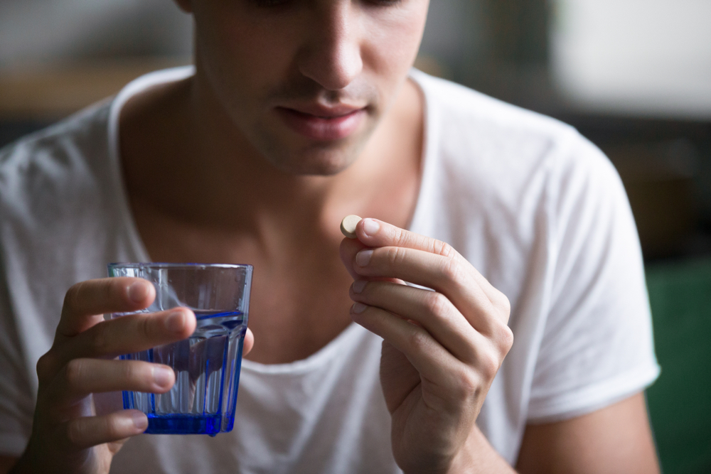 Sick,Ill,Depressed,Man,Holding,Glass,Of,Water,Taking,Pill