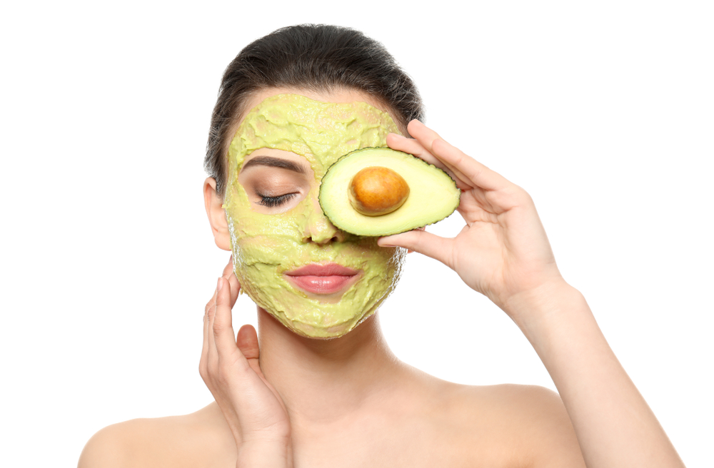 Beautiful,Young,Woman,With,Facial,Mask,And,Fresh,Avocado,On