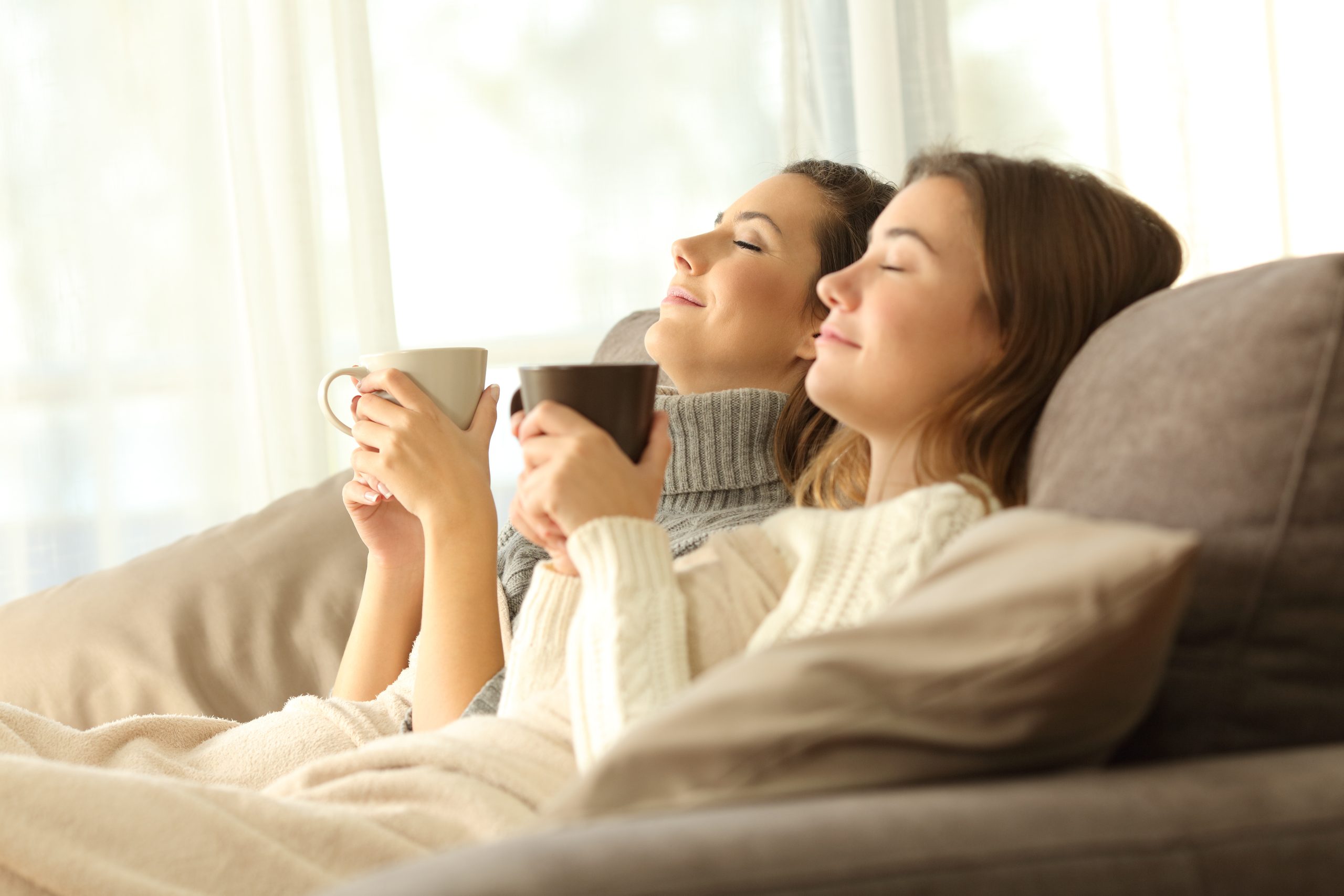 Zwei im Winter entspannte Mitbewohner auf einem Sofa im Wohnzimmer eines Hausinneren