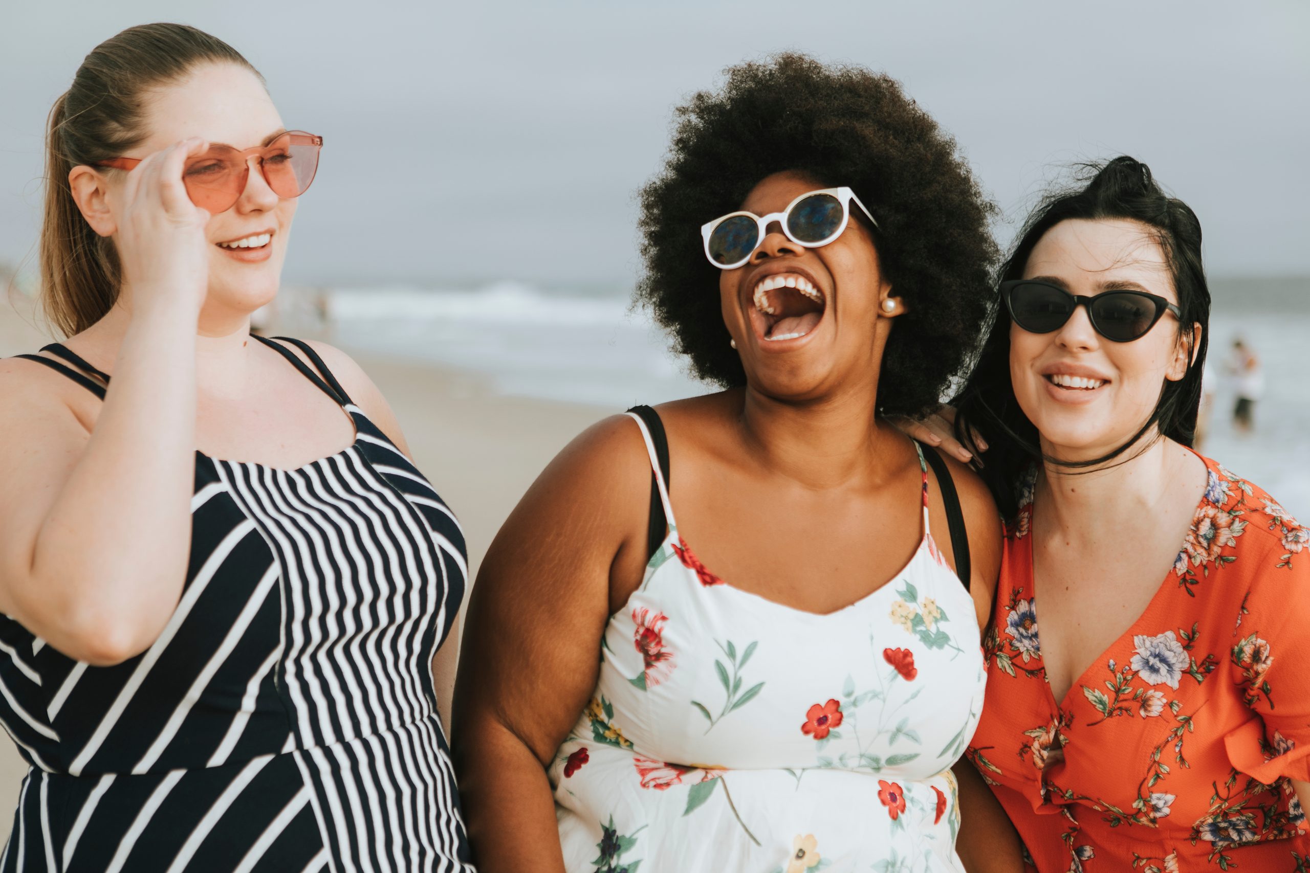 Fröhliche Frauen mit mehr als einer Größe am Strand