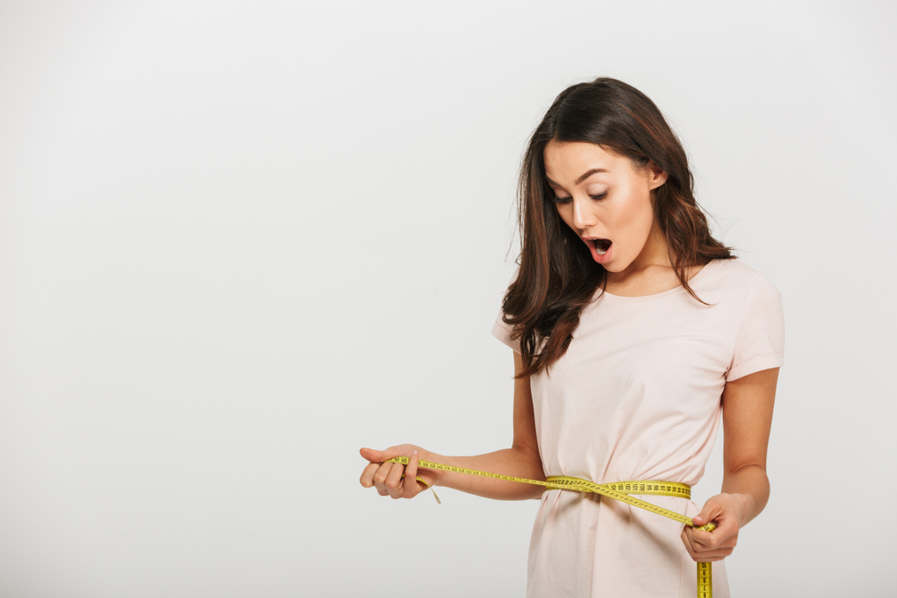 Portrait,Of,A,Surprised,Young,Asian,Woman,Holding,Measuring,Tape