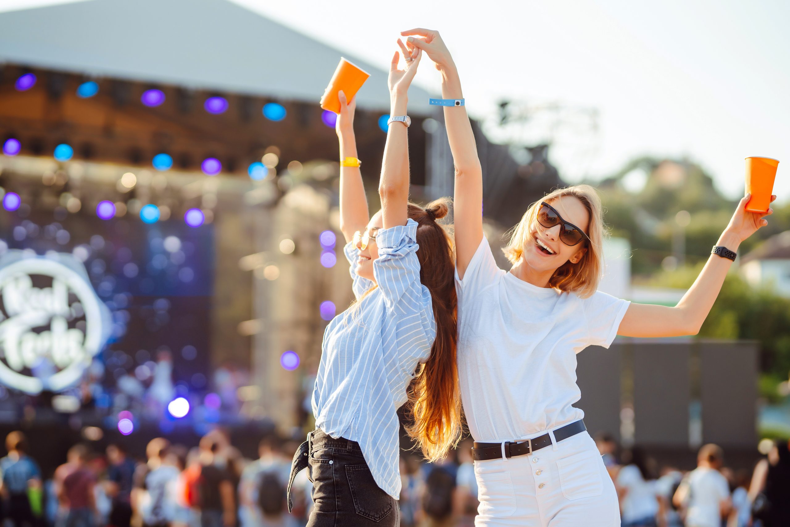 Zwei junge Frau trinken Bier und amüsieren sich auf der Beach Party zusammen. Fröhliche Freundinnen, die Spaß beim Musikfestival haben. Sommerurlaub, Urlaubskonzept.