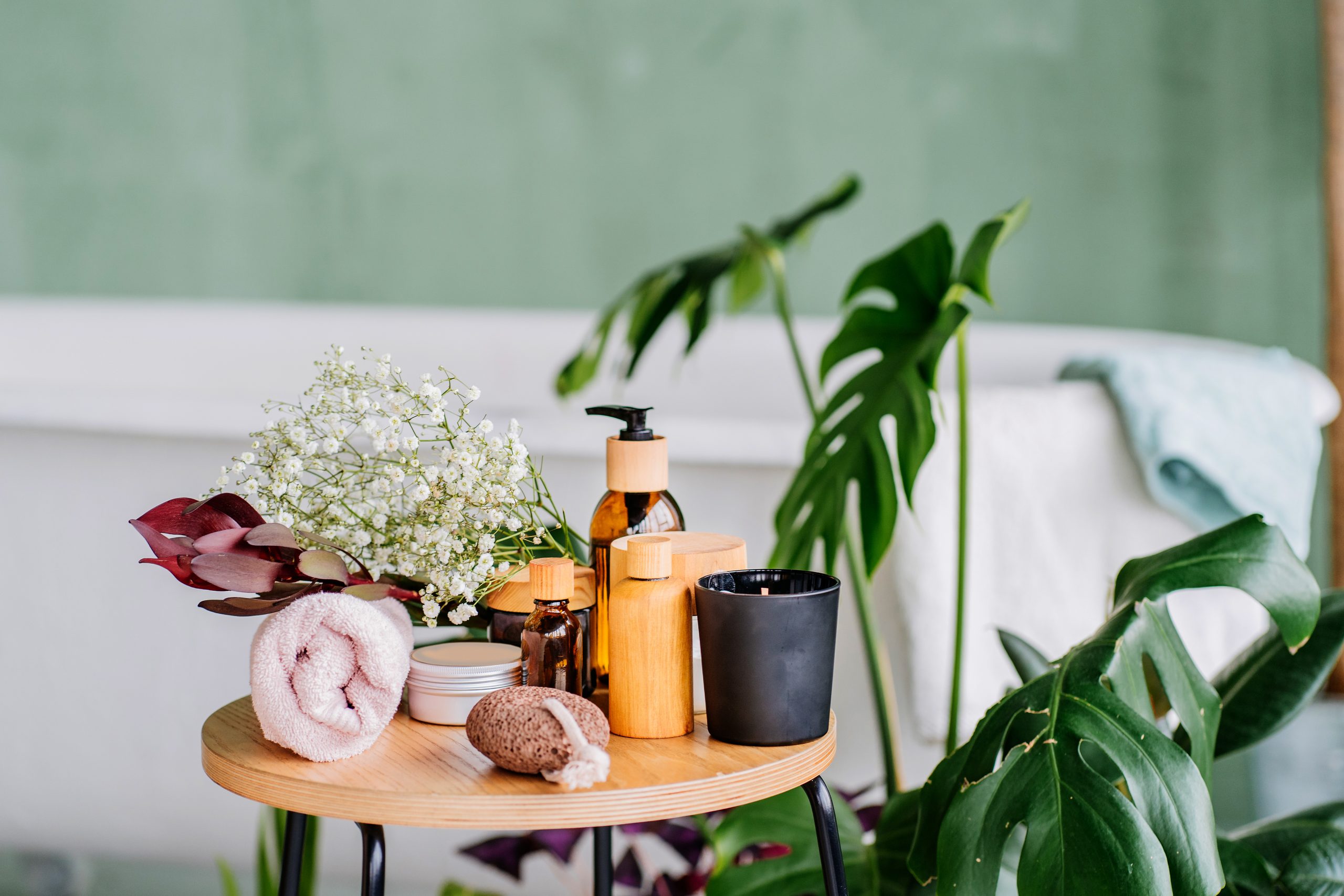 Komfortable Wellness-Set auf Holztisch in modernem öko-natürlichen Innenraum des Badezimmers mit grünen Pflanzen. Umweltfreundliche natürliche Reinigungsmittel und -produkte.