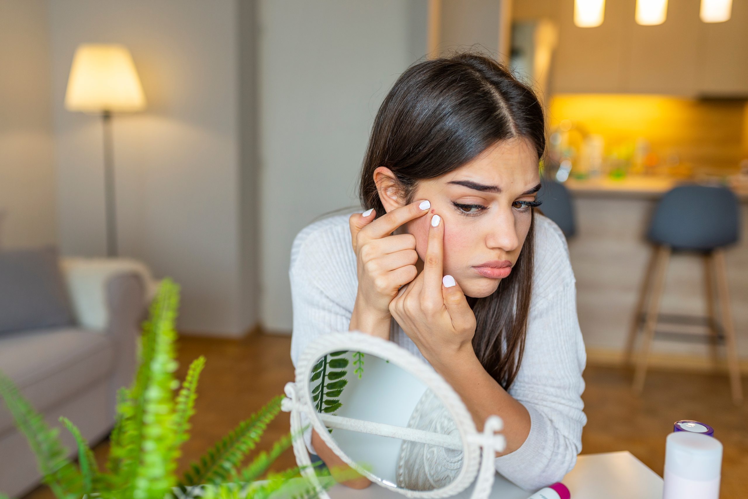 Porträt von schönen jungen Frauen, die beim Betrachten des Spiegels die Pimel quetschen. Pimple auf die Wange. Junge Frau presst ihre Akne vor den Spiegel. Ich bin sicher, dass das verschwinden wird, wenn ich es aufgebe.