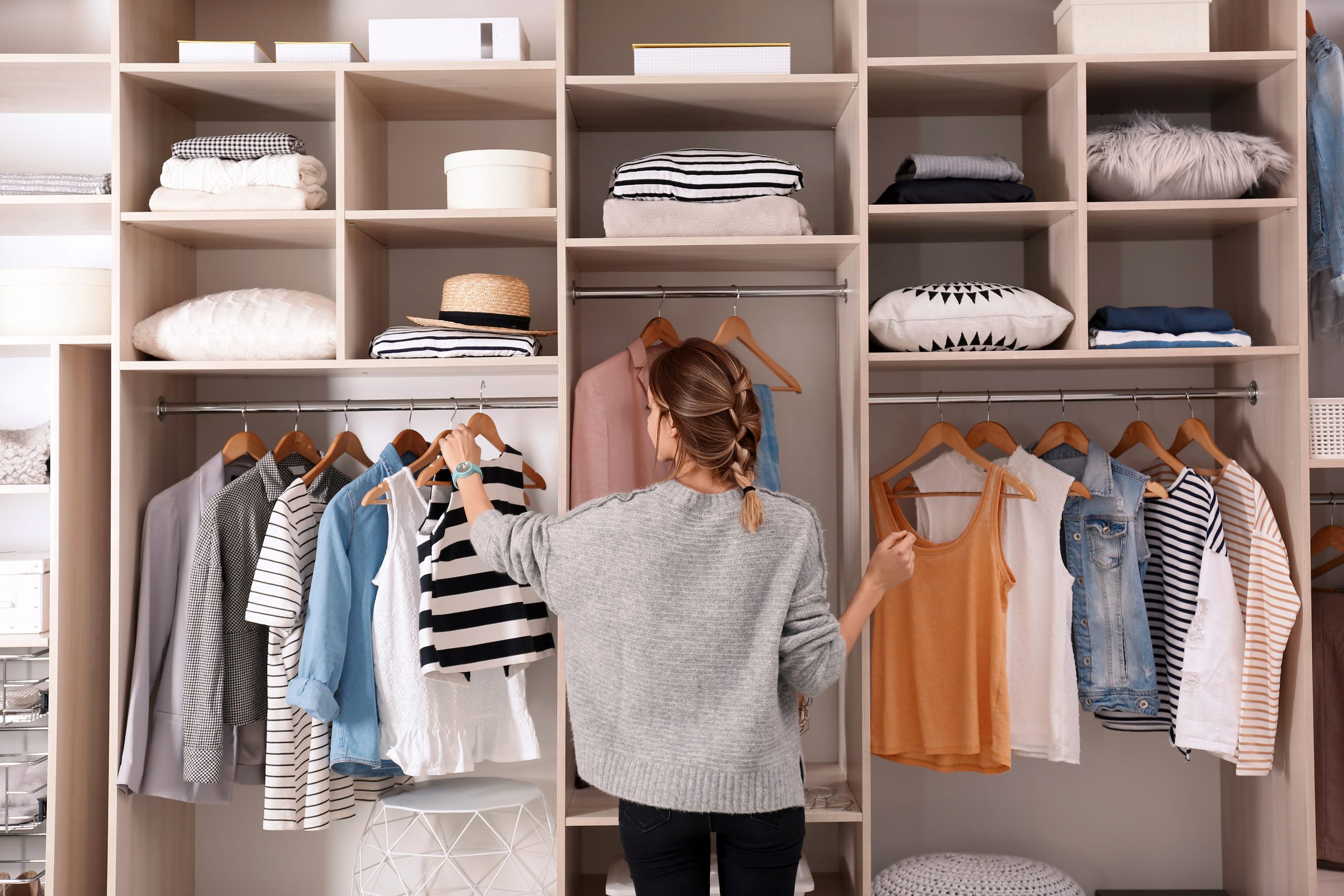 Frauen wählen die Einrichtung aus einem großen Kleiderschrank mit stilvollen Kleidung und Hauskram