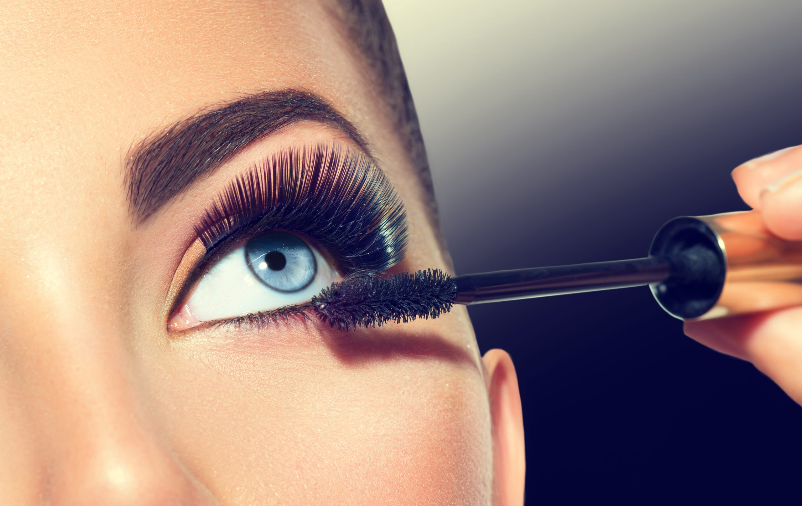 Mascara Anwendung. Lange Leine, Nahaufnahme. Mascara Brush.Eyelashes Schminken Sie auf blaue Augen auf. Augenschminken anwenden, Augenbrauen formen. Schöne weibliche Augen bilden sich