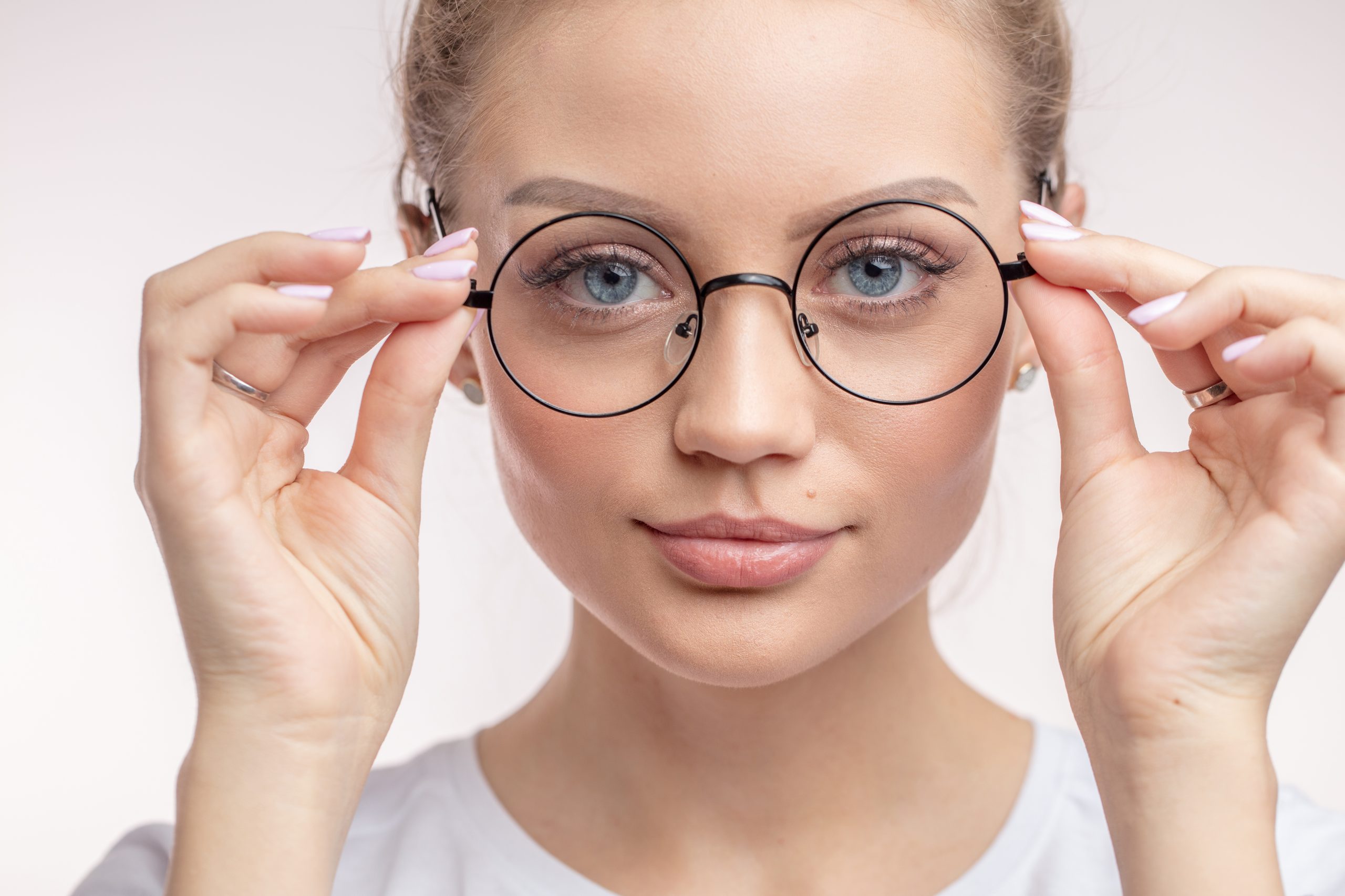 schöne Frau, die eine neue Brille anzieht. Mädchen probiert Augenwäsche an. Weibchen nimmt Brille ab