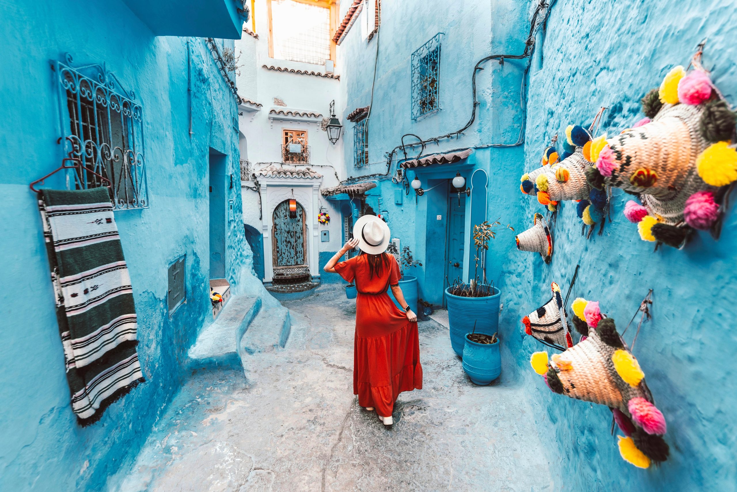 Junge Frau mit rotem Kleid, die die blaue Stadt Chefchaouen, Marocco besucht - Schöner Touristenspaziergang in der marokkanischen Stadtstraße - Das Konzept des Lebens- und Reisens