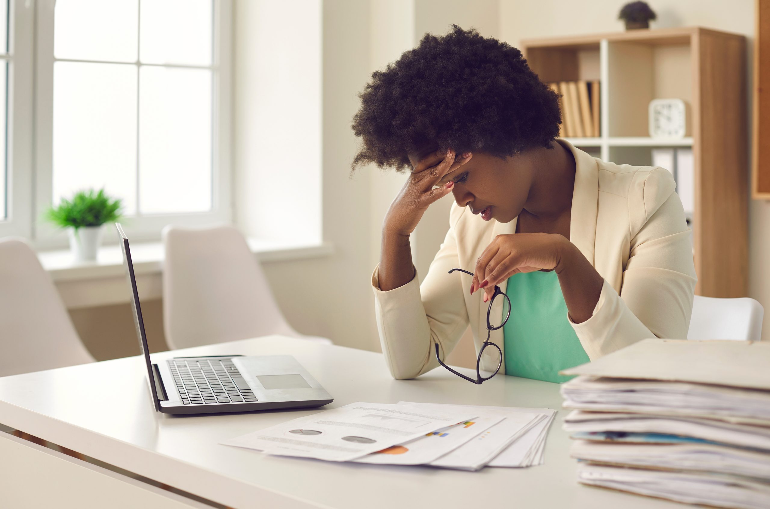 Die afroamerikanische Geschäftsfrau, die der Arbeitsabläufe und Termine müde ist, leidet unter Kopfschmerzen bei der Arbeit. Die entlassene Büroangestellte leidet unter einem Brand. Konzept überarbeitet.