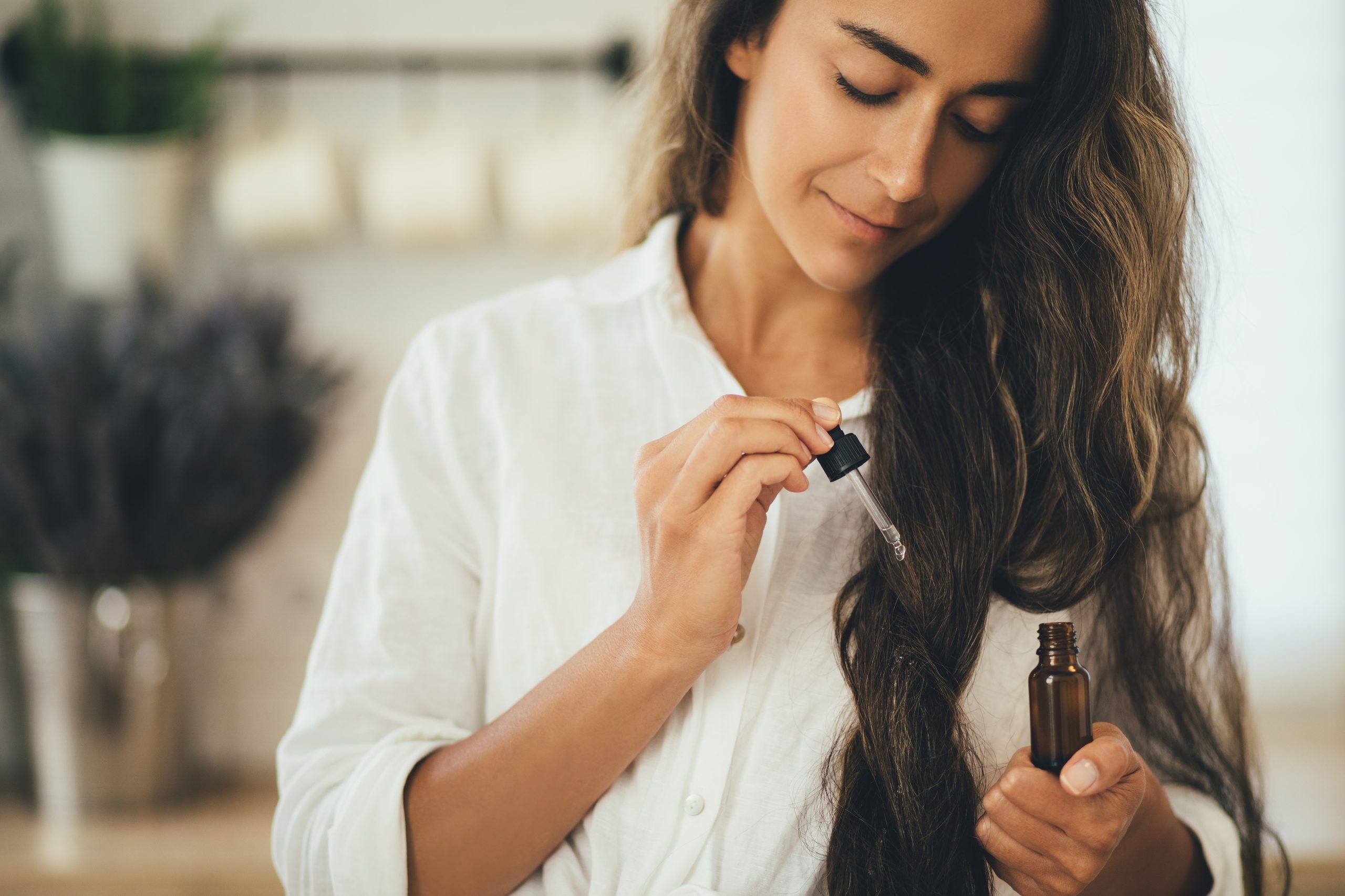 Junge Frau, die natürliches ätherisches Öl auf Haar und Haut aufträgt. Heim- und Beauty-Rituale. Hautpflege.