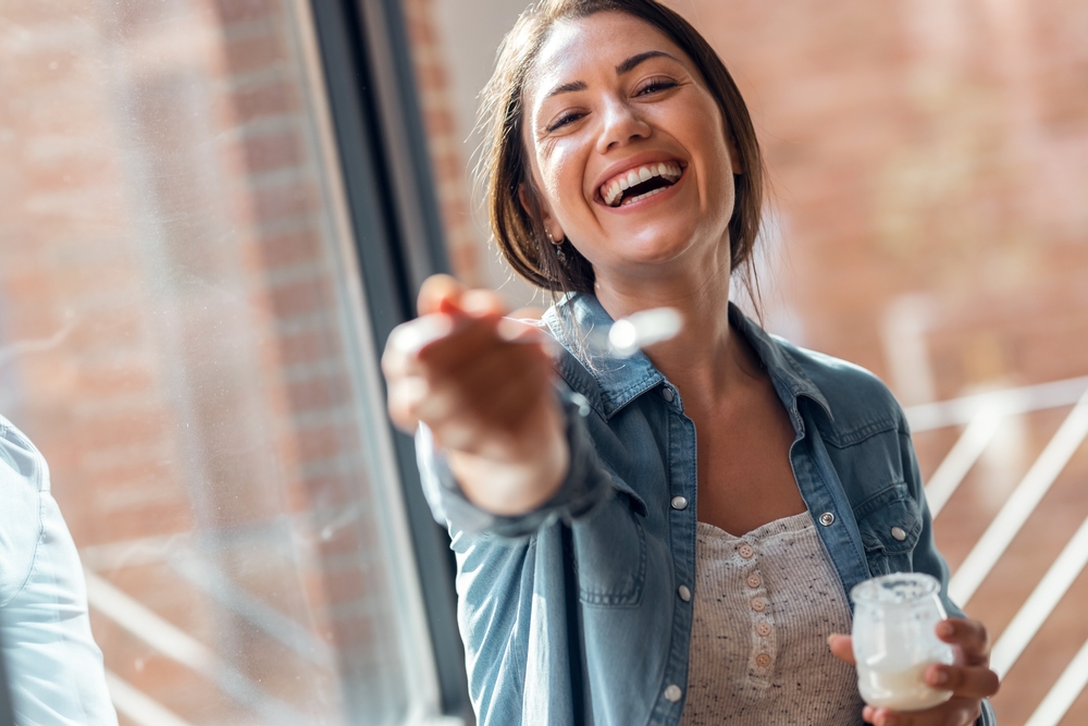 Portrait,Of,Beautiful,Smiling,Woman,Having,Fun,While,Feeding,Yogurt