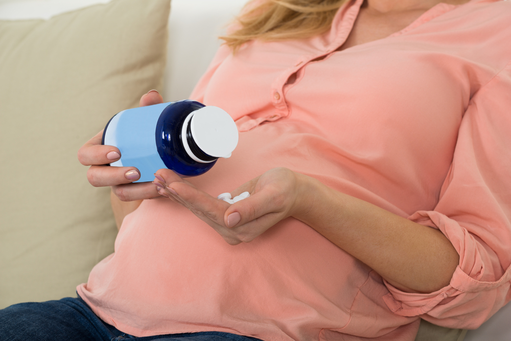 Midsection,Of,Pregnant,Woman,Pouring,Pills,In,Hand,From,Bottle