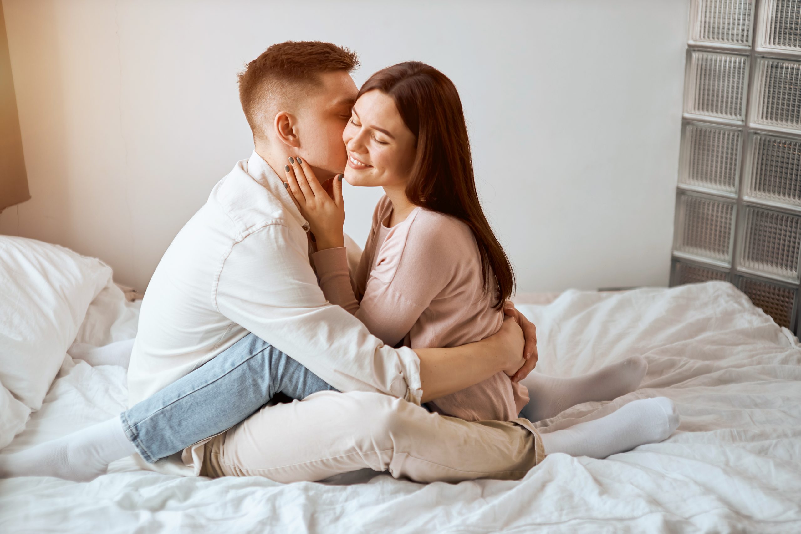 Mann und Frau umarmen sich auf Bett.