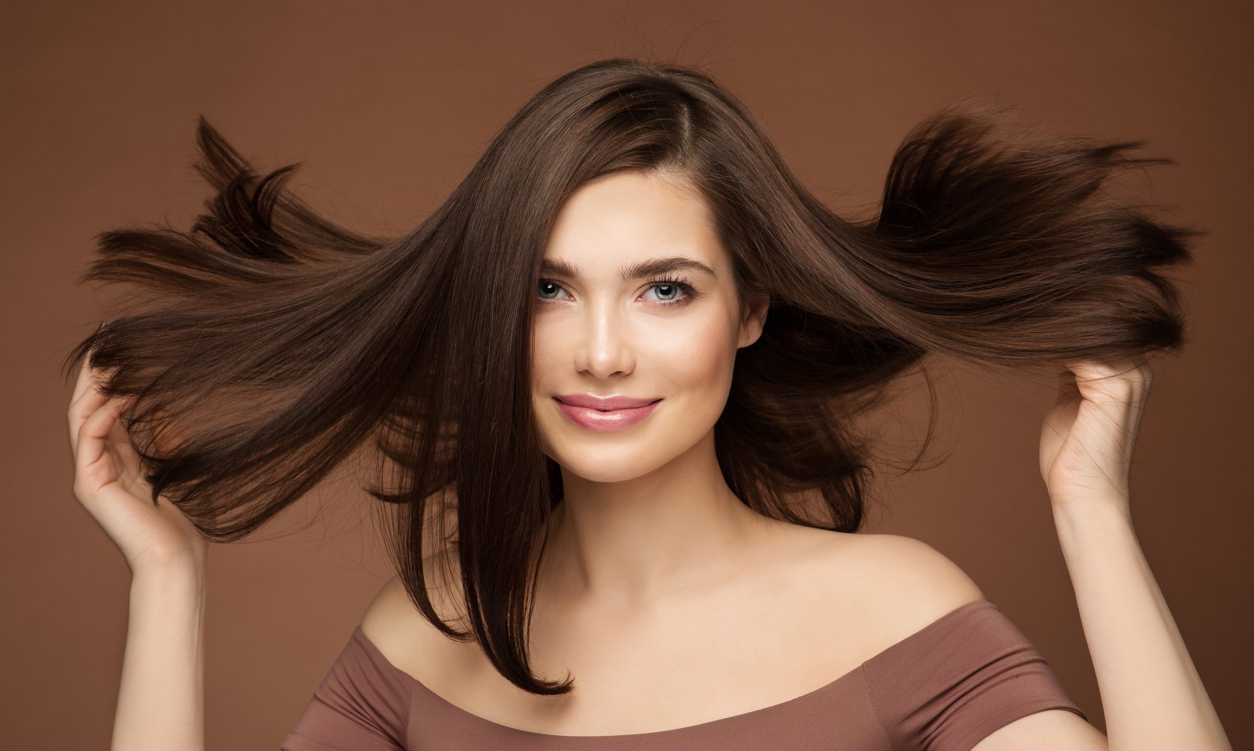 Friseur-Schönheitsmodell. Brunette Woman mit Straight Hairstyle fliegen auf Wind über Dunkelbeige. Junge lächelnde Mädchen mit glatter Haut Make-up