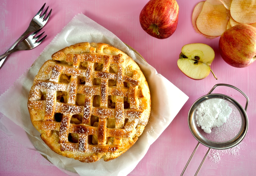 Apple,Pie.,Pink,Background.,With,Apples,,Fork,And,Powdered,Sugar
