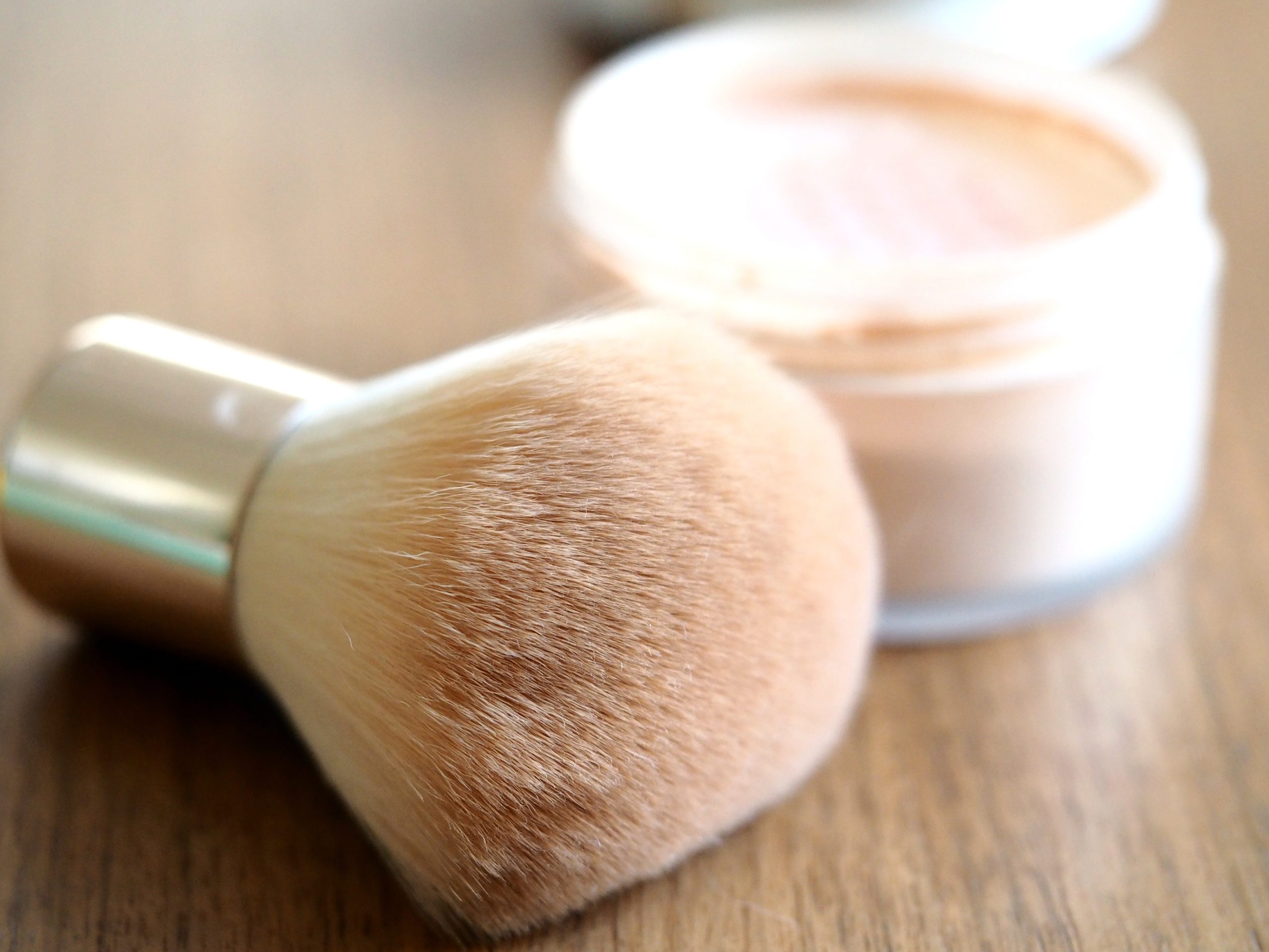 kabuki brush and loose powder wooden background close up