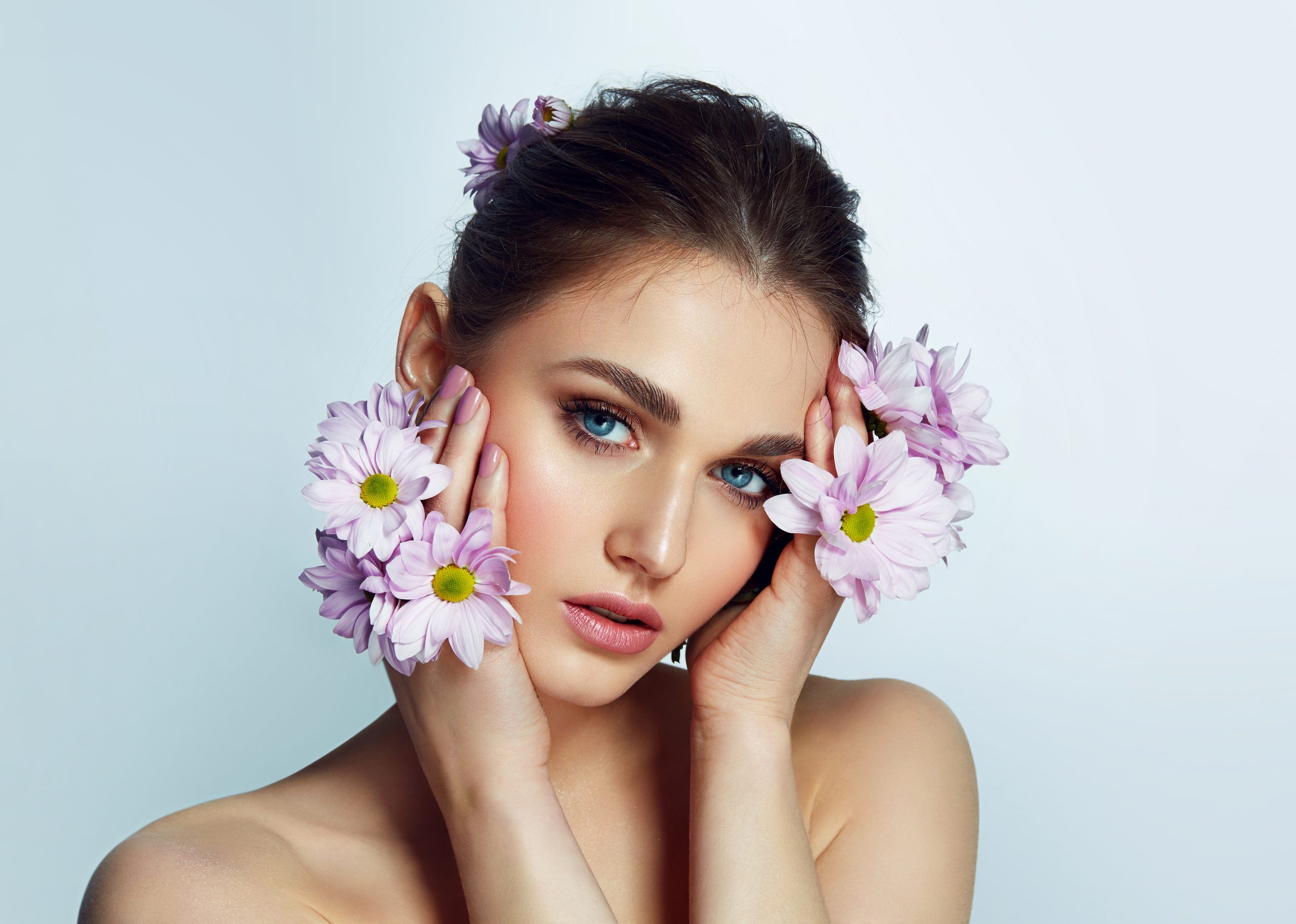 Porträt eines wunderschönen, natürlichen, blauäugigen Mädchens mit lischen Blumen in freier Wildbahn. NacktMake-up.