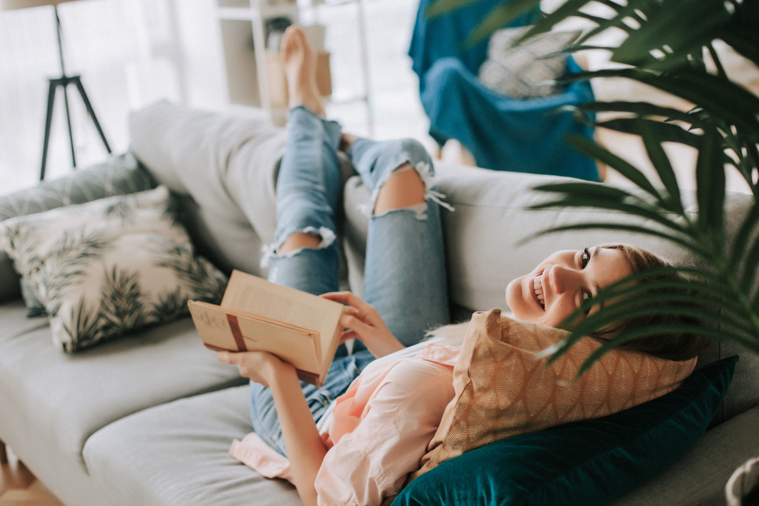 Junge schöne Mädchen lesen ein Buch auf dem Sofa.