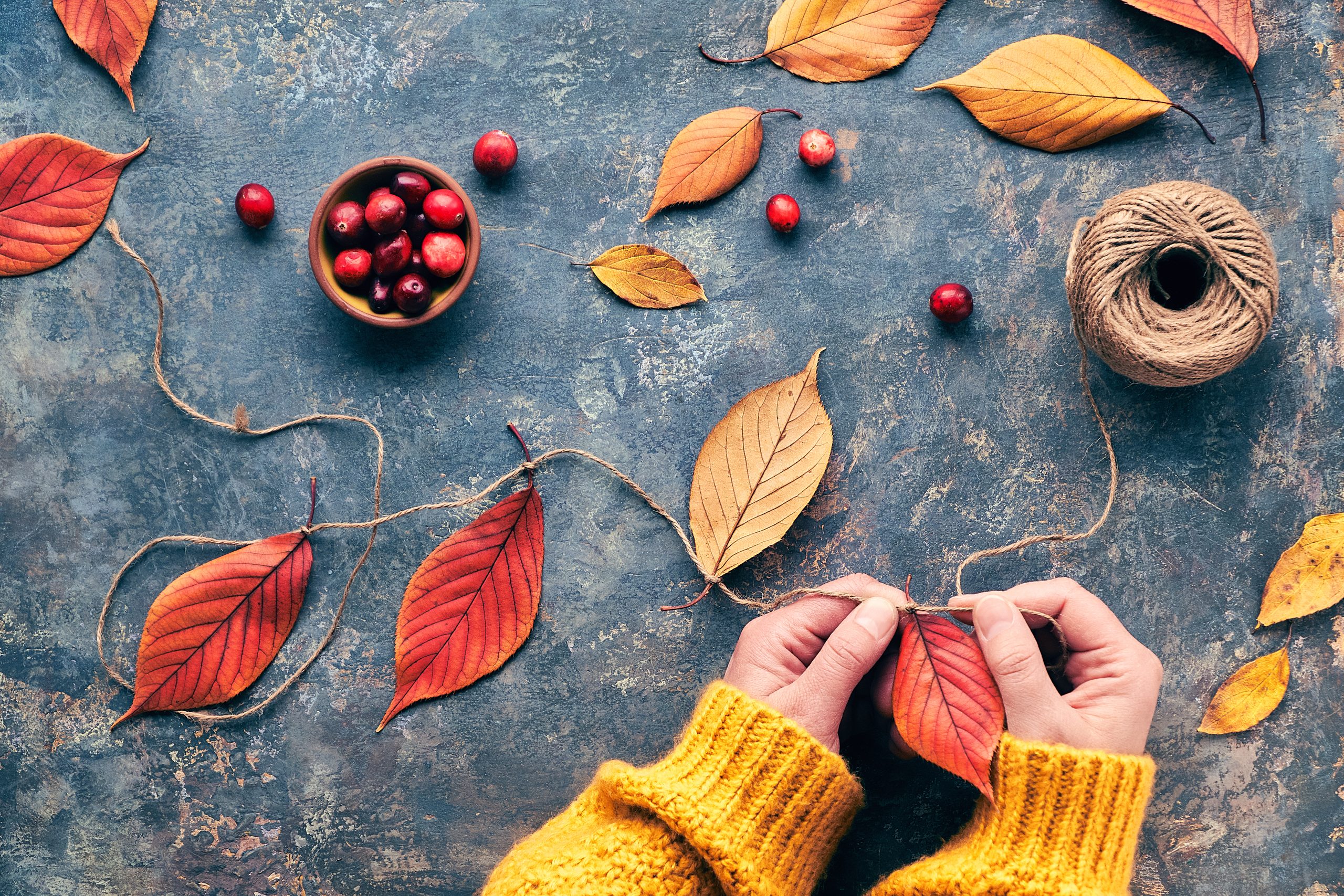 Herbstdekorationen handgefertigt aus Naturmaterialien. Garland mit und lebendigen roten Herbstblättern bauen.