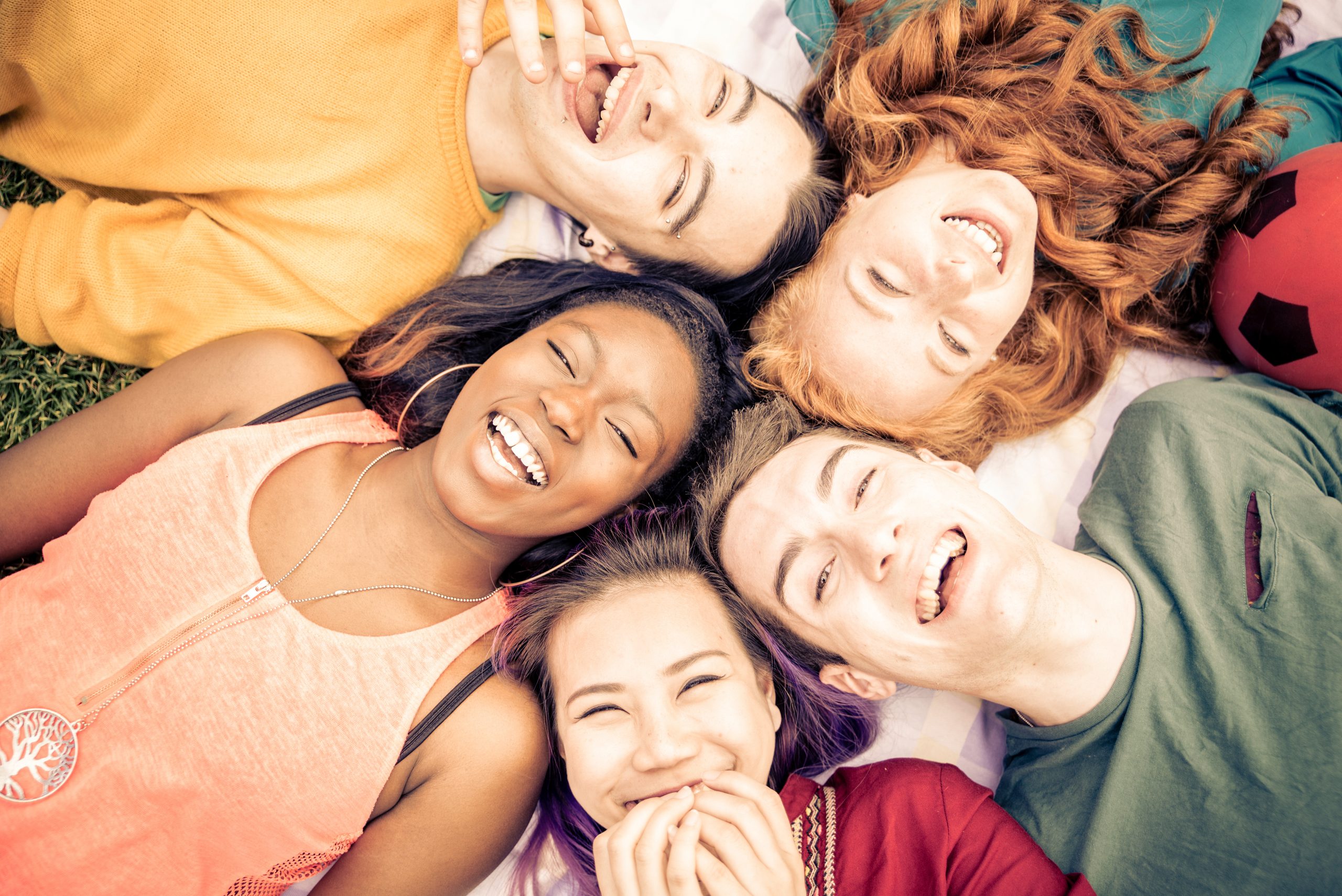 Gruppe von Freunden, die draußen laut lachen, gute und positive Stimmung teilen.