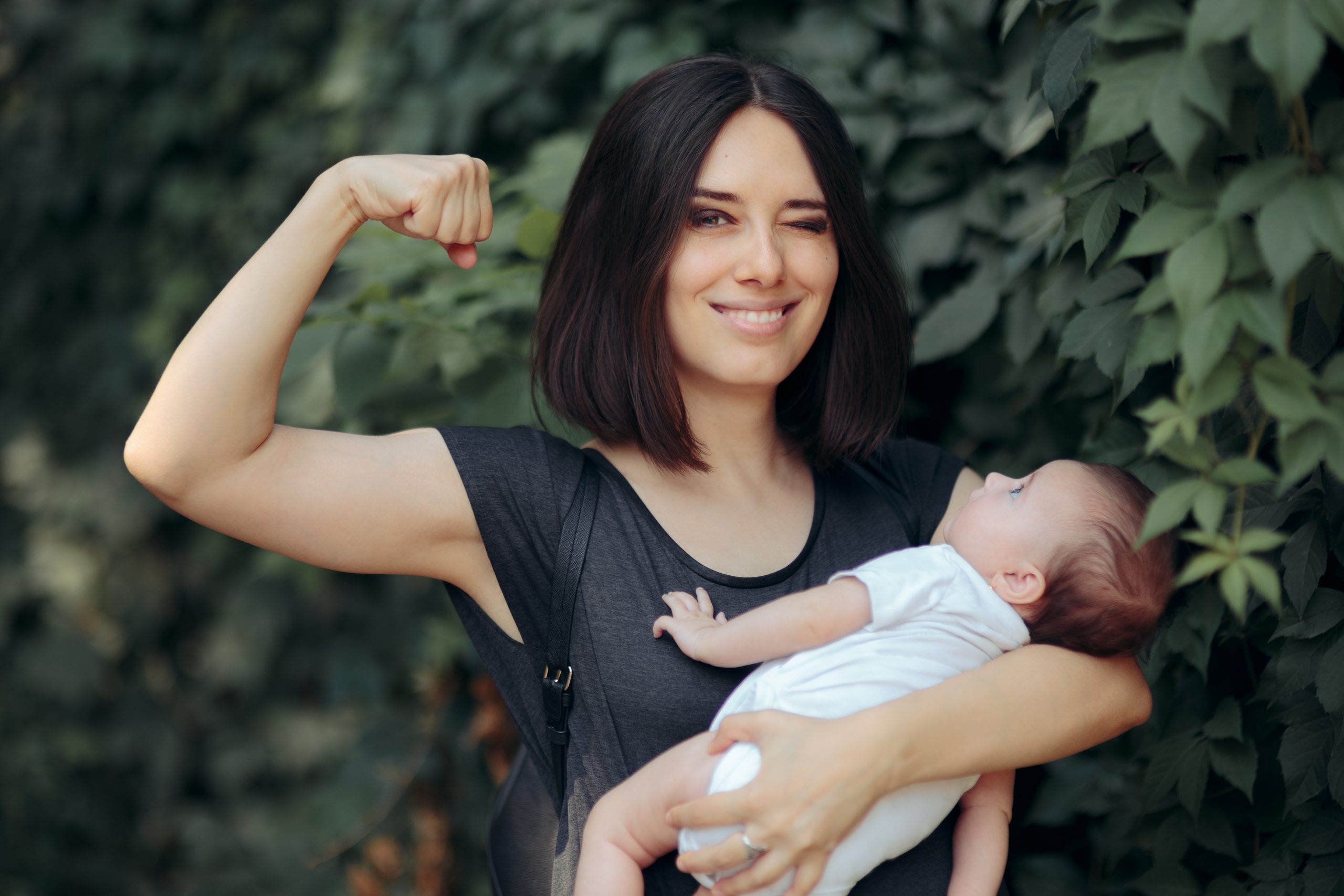 Mutter mit Baby und Strong-Pose.