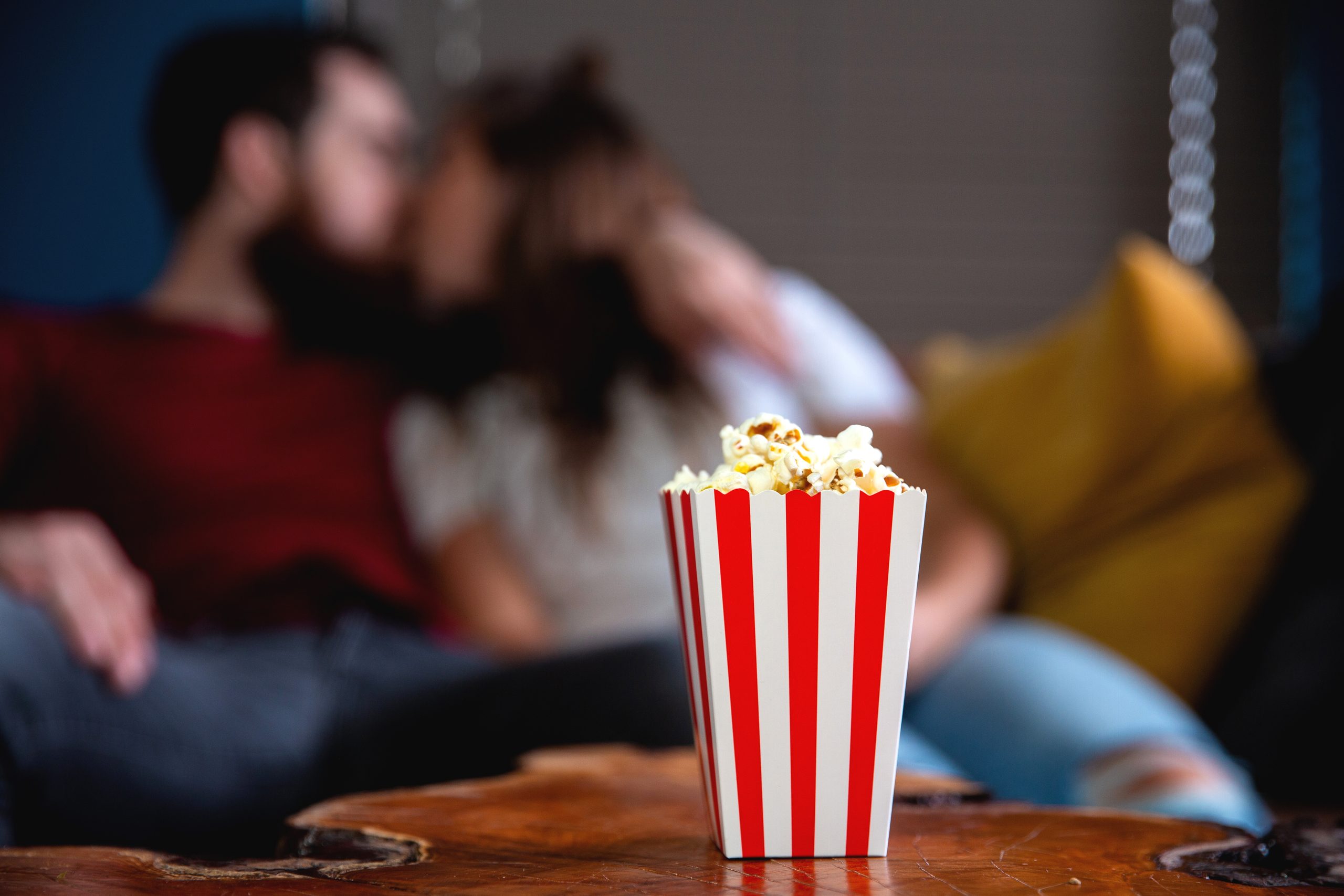 Ein junges Ehepaar, das liebt, fernzusehen, am Abend romantische Verabredung auf dem Sofa liegen und Popcorn essen