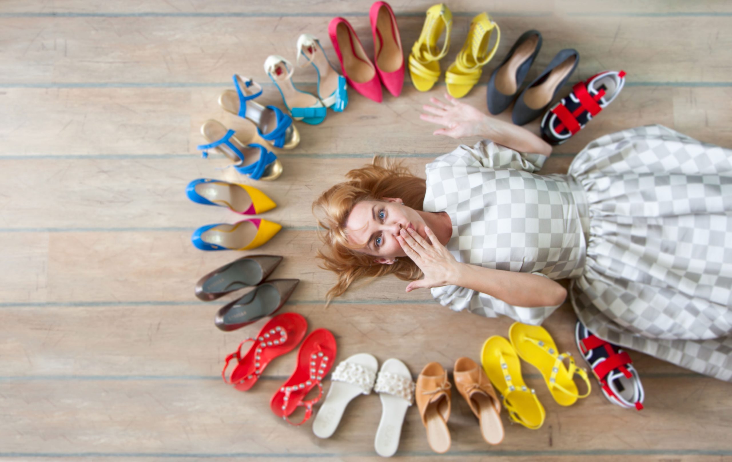 Viele bunte Frauenschuhe auf dem Boden. Eine Frau wählt ihre Schuhe.