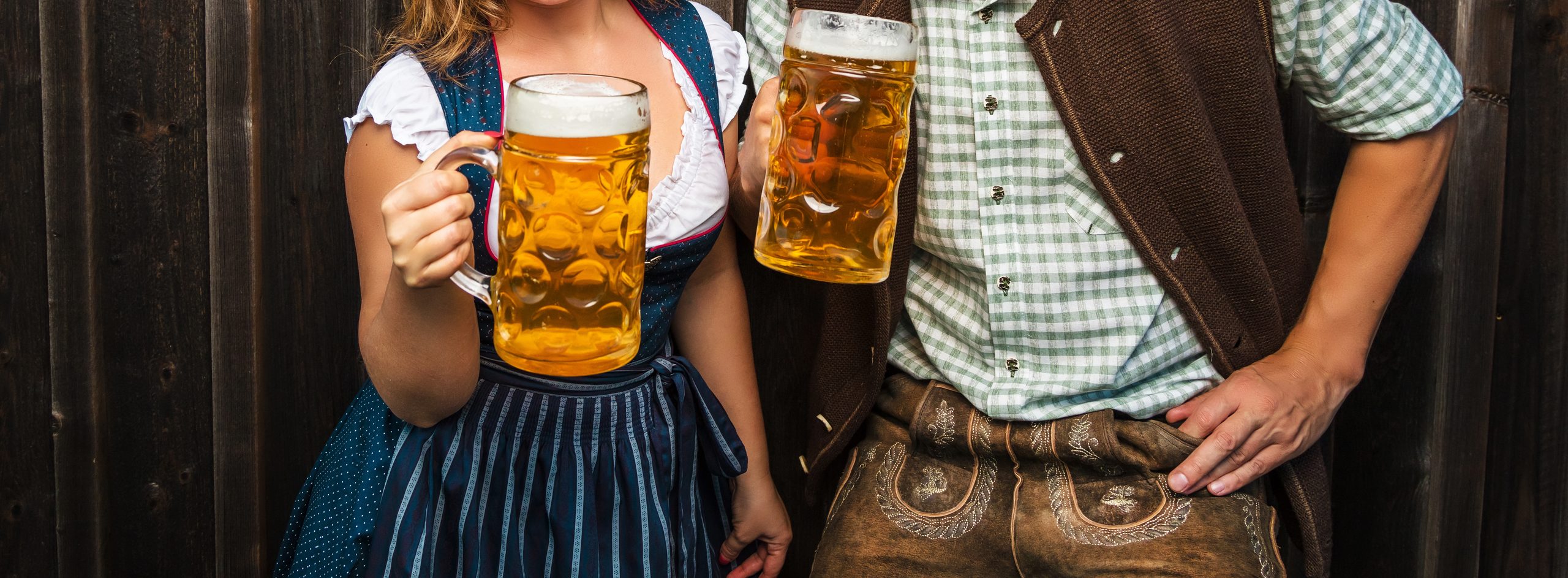 Junge Frau und Mann mit Bierglas und Brezel auf Holzhintergrund .Oktoberfest-Konzept