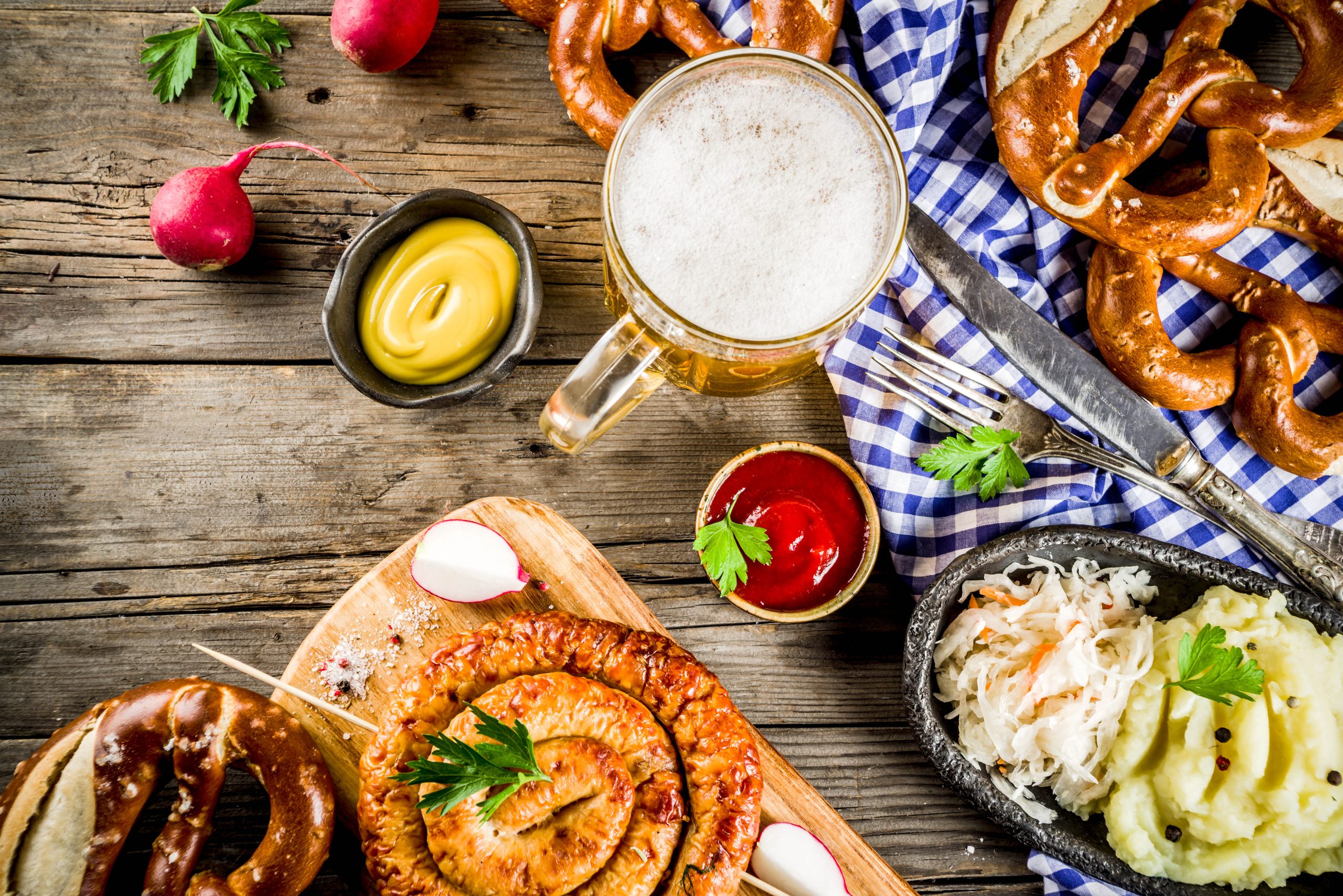 Oktoberfest-Speisekarte, bayerische Würstchen mit Brezeln, Kartoffelbretter, Sauerkraut, Bierflasche und alter rustikaler Holzhintergrund, Kopienraum oben