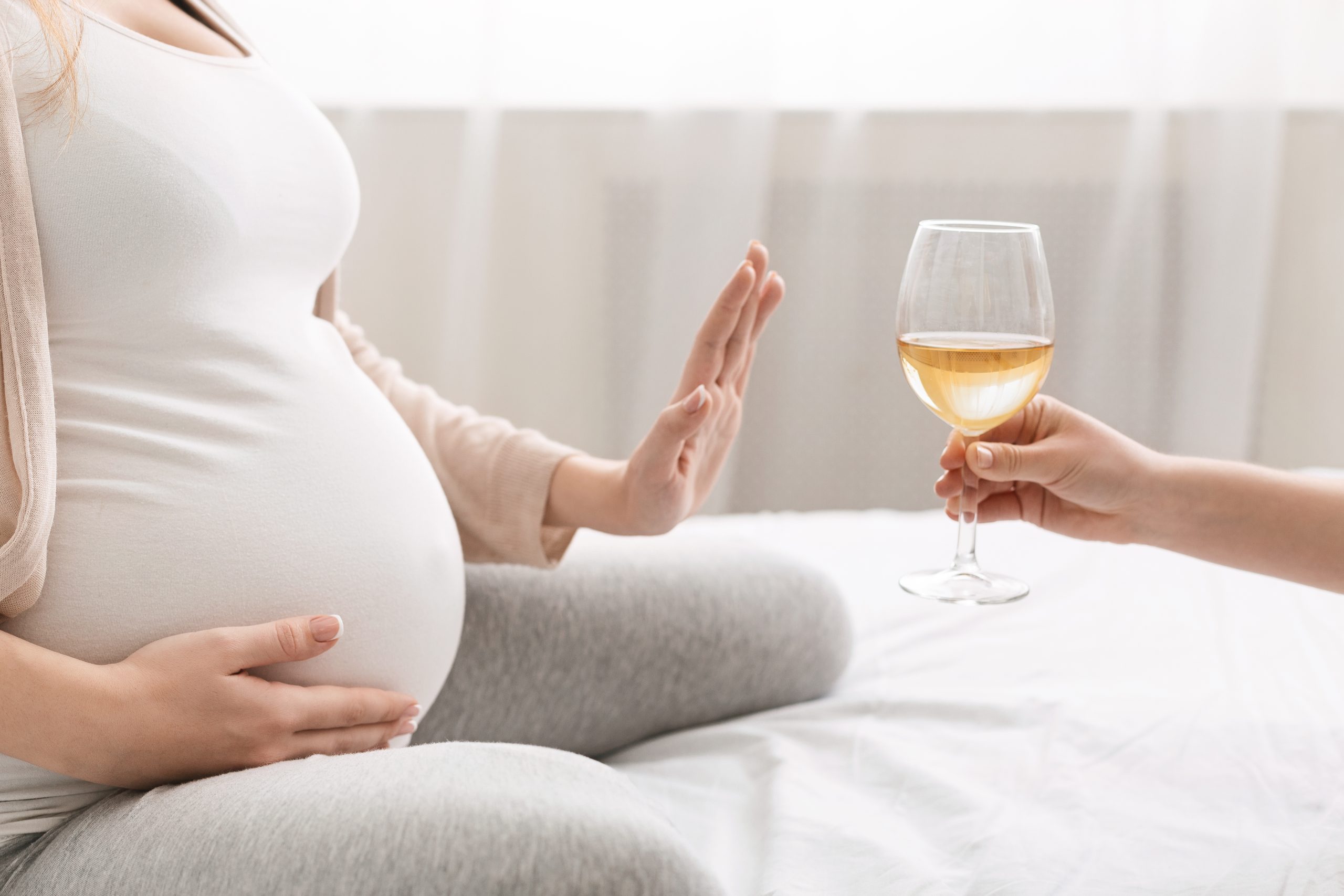 Eine schwangere Frau lehnt ein Glas Wein ab.